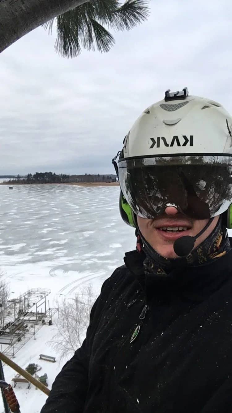 Helmeted arborist beside a snow-covered field.