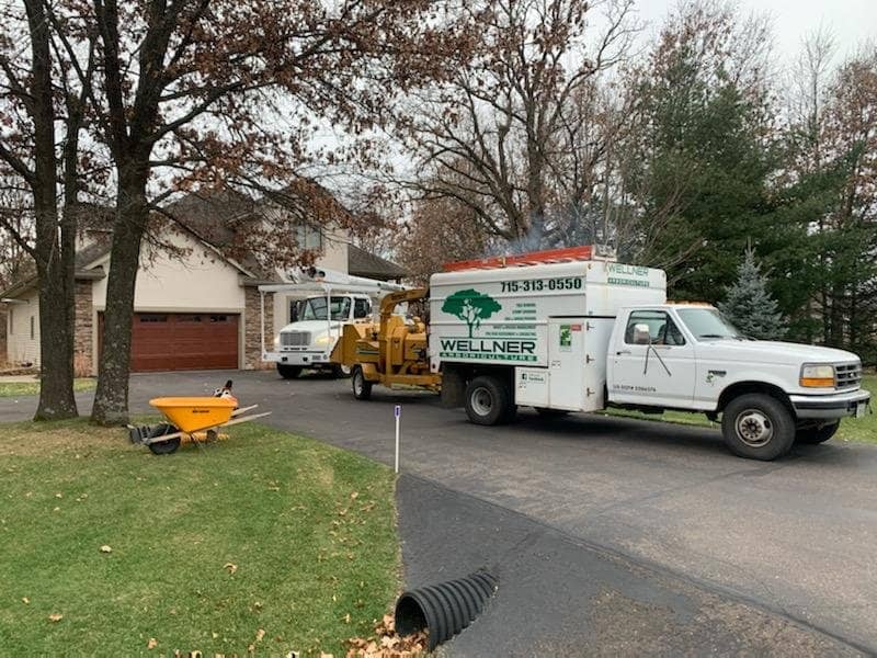 Wellner truck and wood chipper parked in a residential driveway.