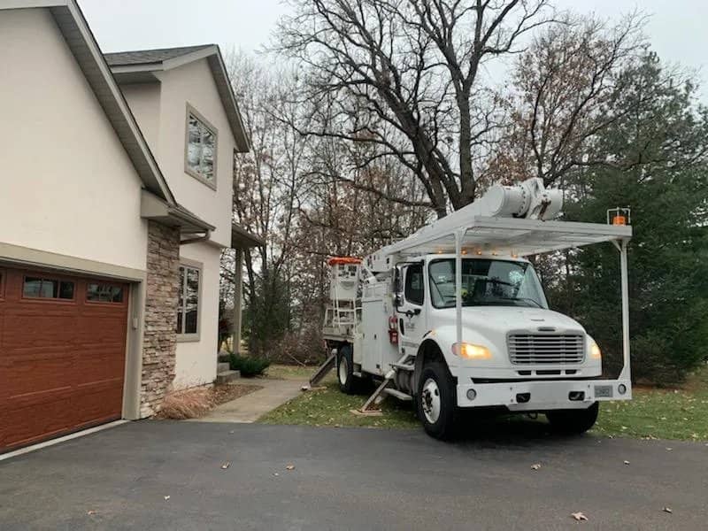 Bucket truck parked beside a house with its boom folded.