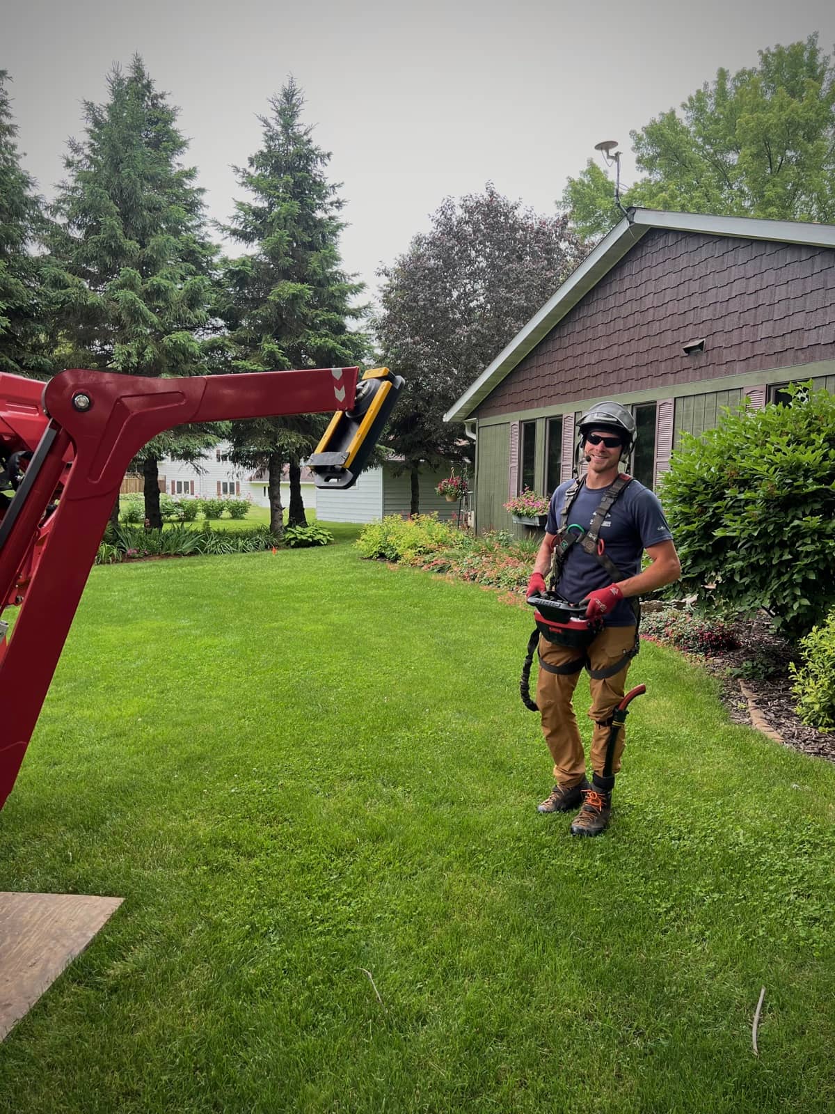 Arborist operating equipment beside a red lift.