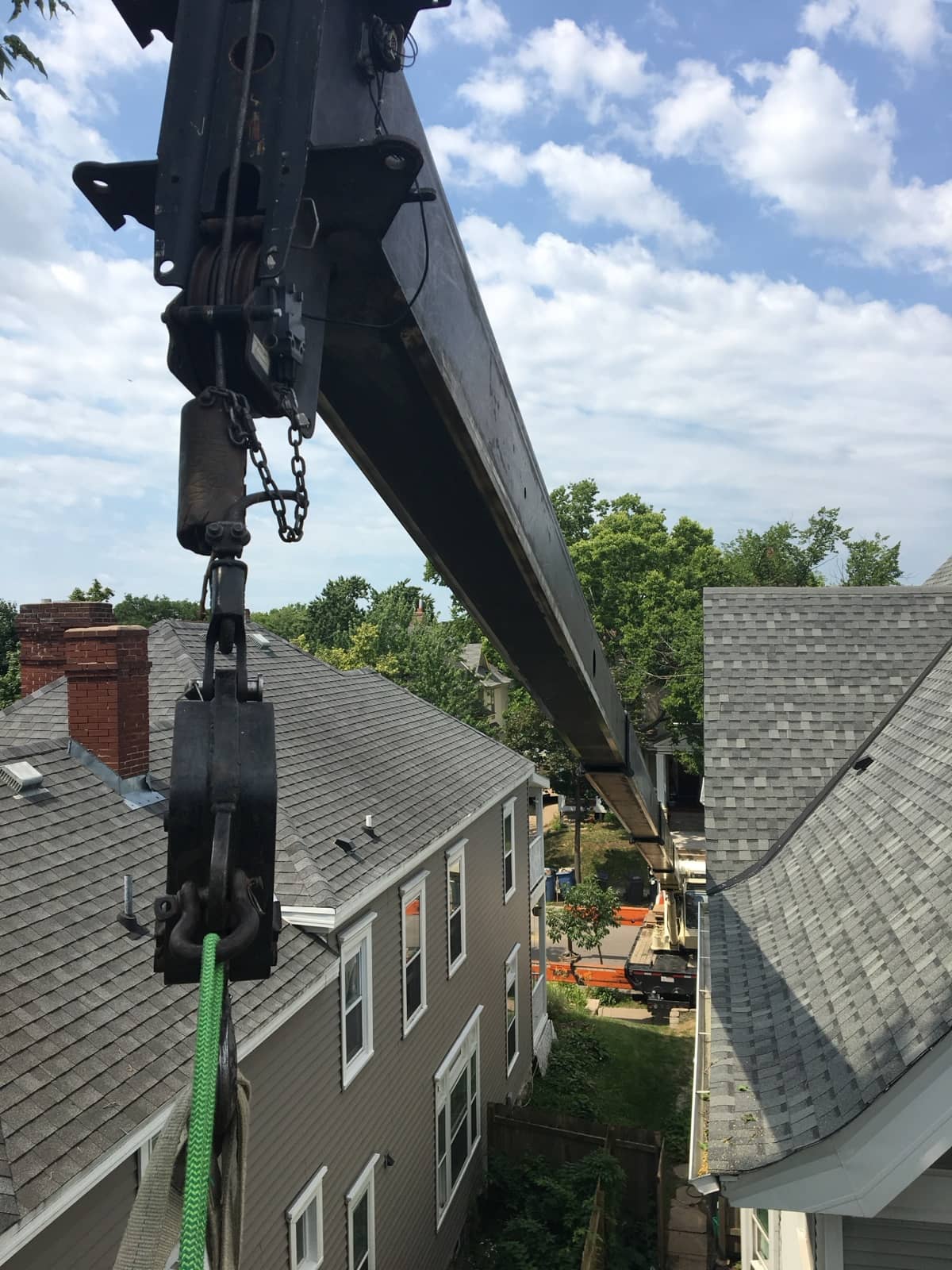 Crane boom and rigging above the roofs of two houses.
