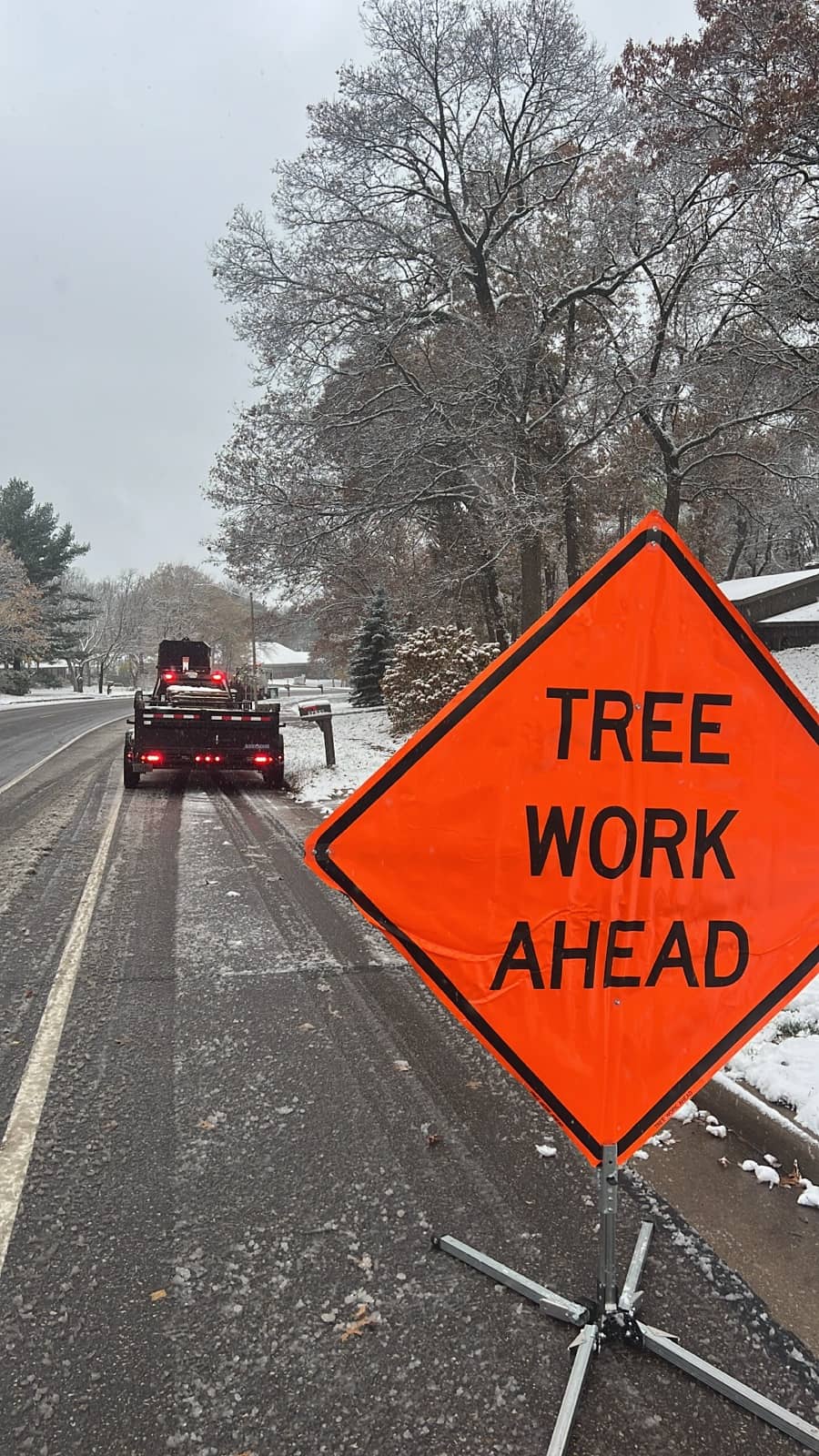 Roadside sign reading "Tree Work Ahead" beside a work truck.