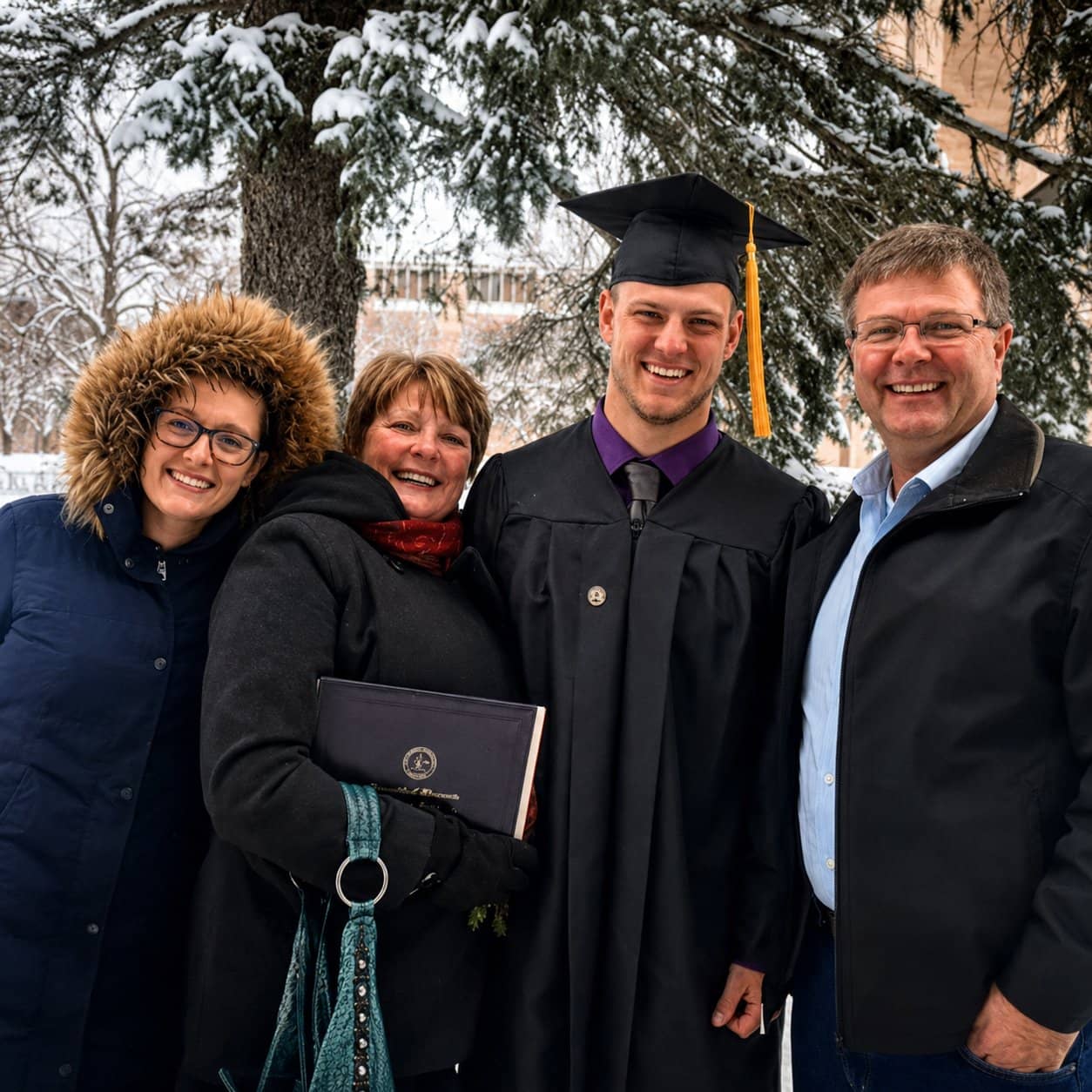 Four people posing outdoors with a graduate